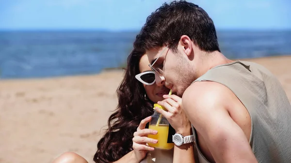 Homem Óculos Escuros Bebendo Suco Laranja Perto Namorada Praia — Fotografia de Stock