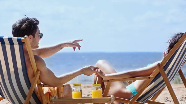 Man Sunglasses Pointing Finger Holding Hand Girlfriend Deck Chair Orange — Stock Photo, Image