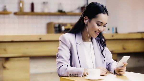 Усміхнена Азіатська Жінка Костюмі Слухає Музику Навушниках Використовує Смартфон Біля — стокове фото
