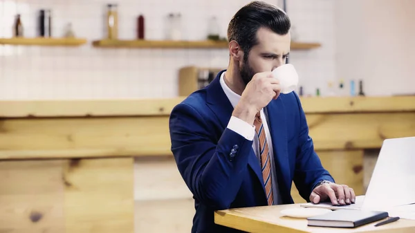 Bärtiger Geschäftsmann Anzug Trinkt Kaffee Während Laptop Café Benutzt — Stockfoto