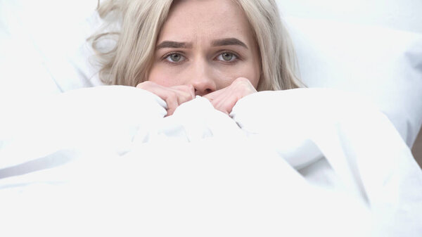 молодая расстроенная женщина смотрит в камеру в постели