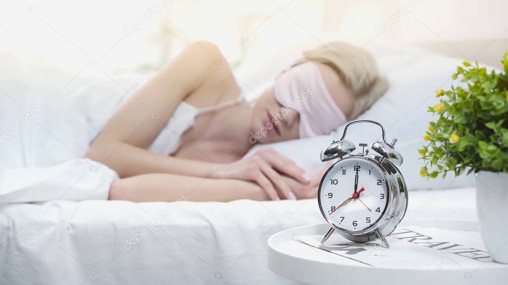 young blonde woman in sleeping mask lying in bed