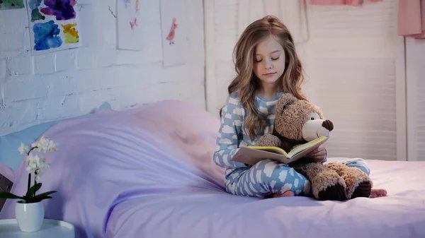 Preteen Kid Holding Soft Toy Reading Book Bed — стоковое фото