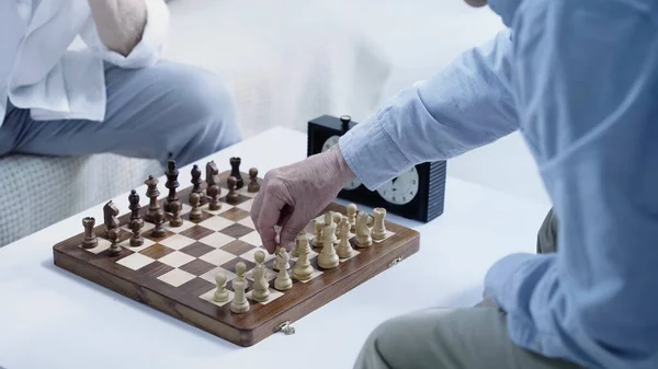 cropped view of senior chess players gaming at home