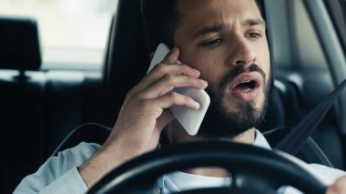 surprised man talking on smartphone while driving car