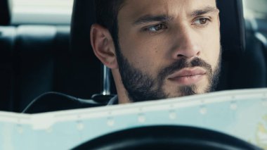portrait of bearded man sitting in automobile with map