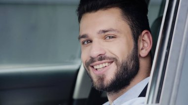portrait of happy young man driving car and smiling at camera