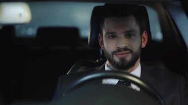 young and positive businessman traveling in auto at night