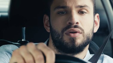 young and concentrated man driving car and looking ahead