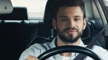 positive young man smiling while traveling in car