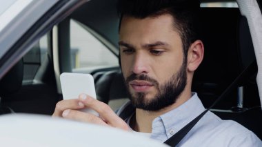 thoughtful man estimating route on smartphone while sitting in car