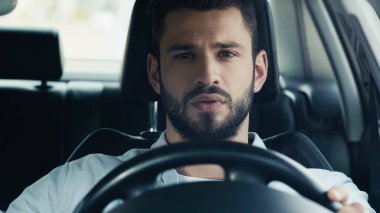 young and attentive man driving auto and looking ahead clipart