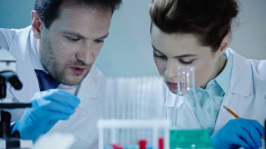 two scientists in latex gloves and white coats looking down in laboratory