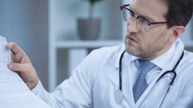 cardiologist in glasses and white coat talking while looking at cardiogram in hospital 