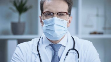 doctor in glasses and medical mask looking at camera in clinic
