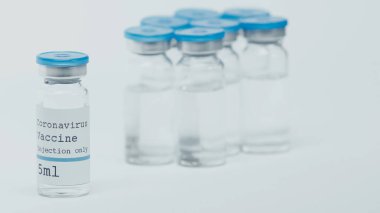 close up of glass bottles with coronavirus vaccine lettering isolated on white 