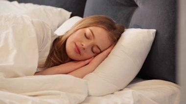 Blonde woman sleeping on bed at home 