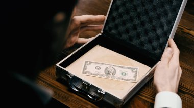 Blurred businessman holding case with unique dollar banknote on table
