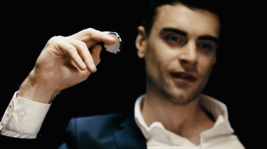 Blurred businessman holding poker chip isolated on black 