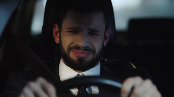 frustrated businessman crying while driving car at night