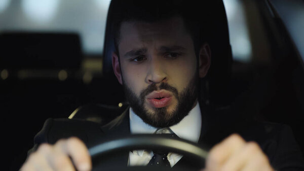 worried man in formal wear driving automobile in evening