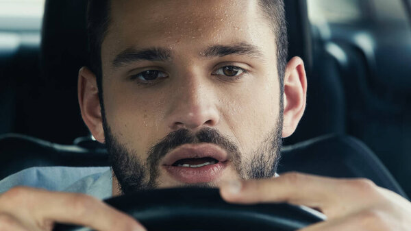 portrait of man with sweat on forehead driving car in hot summer day