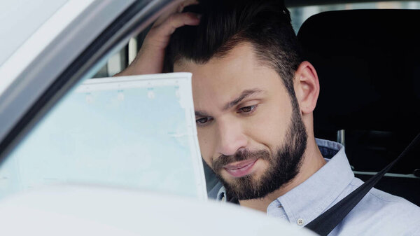 discouraged man sitting in auto and looking at map