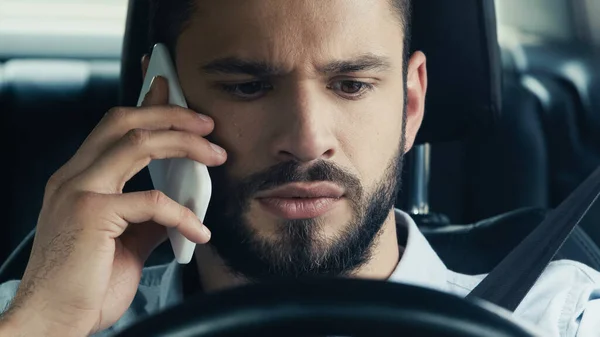 young and tense man talking on cellphone in car