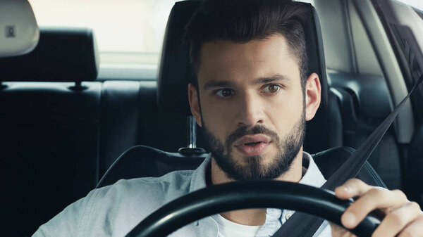 tense young man driving automobile and looking ahead