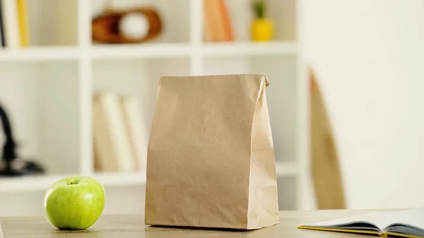 tasty apple and paper bag with lunch on wooden table