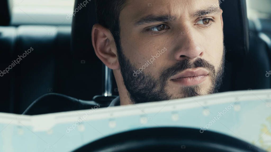 Portrait of bearded man sitting in automobile with map
