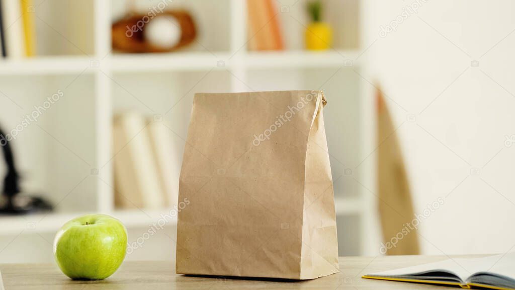 tasty apple and paper bag with lunch on wooden table
