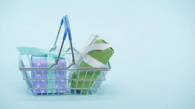 Mavi arka planda paketlenmiş hediye kutularıyla alışveriş sepeti.