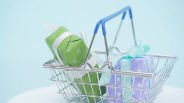 Mavi arka planda paketlenmiş hediye kutularının olduğu alışveriş sepetinin görüntüsünü kapat
