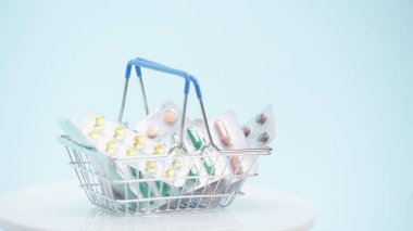 Mavi üzerinde farklı ilaçlar bulunan küçük bir alışveriş sepeti. 