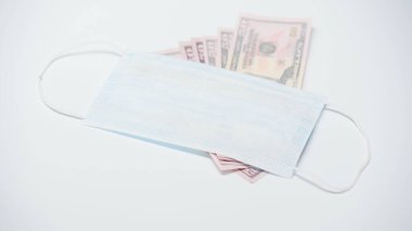 Beyaz arka planda dolar banknotları üzerinde koruyucu tıbbi maske