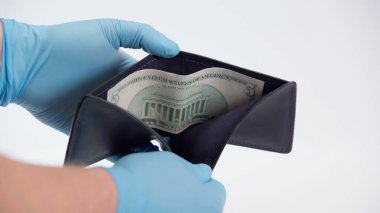 Lateks eldivenli bir insan beyaz cüzdanında dolar banknotunu gösteriyor.