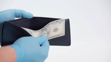 Beyaz banknot ve cüzdan tutan lateks eldivenli insan görüntüsü.