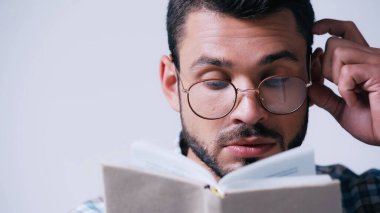 Gözlüklü düşünceli inek öğrenci. Bulanık kitap okuyor ve gri kafaya dokunuyor.