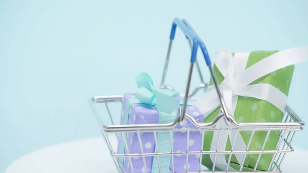 shopping basket with wrapped gift boxes on blue background