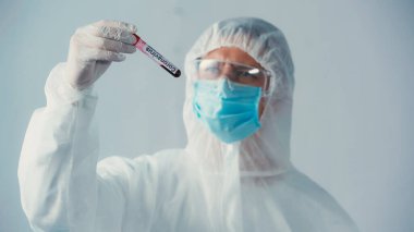 Koronavirüs testine bakan koruyucu gözlüklü ve koruyucu giysili virolog gri renkte izole edilmiş.