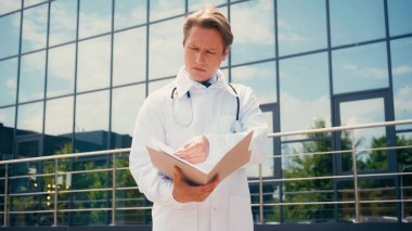 Kliniğin yakınındaki dosyalara bakan düşünceli bir doktor.