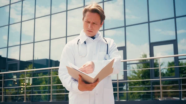 Στοχαστικός Γιατρός Ψάχνει Στο Φάκελο Έγγραφα Κοντά Στην Κλινική Εξωτερικούς — Φωτογραφία Αρχείου