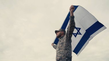 İsrail 'in ulusal bayrağını taşıyan üniformalı askerin arka planda gökyüzü olan düşük açılı görüntüsü 
