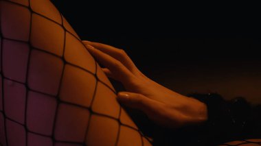 Tutkulu bir kadının bacağa dokunuşunun görüntüsü siyah arka planda sıkıca bağlı. 