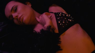 Sütyenli, siyah arka planda ışıklandırmalı seksi bir kadın. 