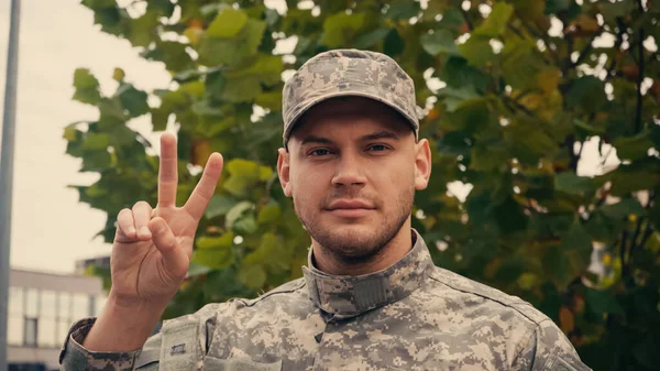 Jovem Soldado Uniforme Boné Mostrando Sinal Paz Perto Árvore Livre — Fotografia de Stock