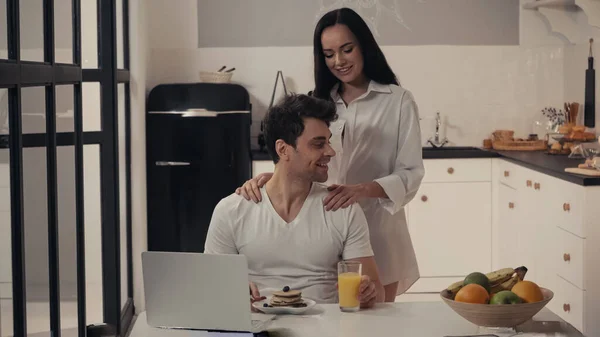 Sexy Woman Hugging Shoulders Happy Man Breakfast Laptop Kitchen — Stock Photo, Image