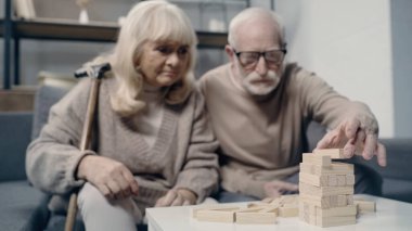 blurred and senior couple with dementia playing in blocks wood game together  clipart