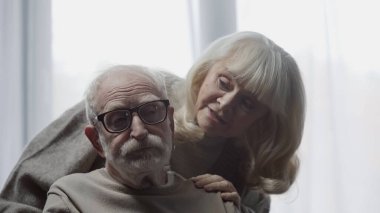 Yaşlı kadın bunamış kocasını gözlükleriyle sakinleştiriyor. 
